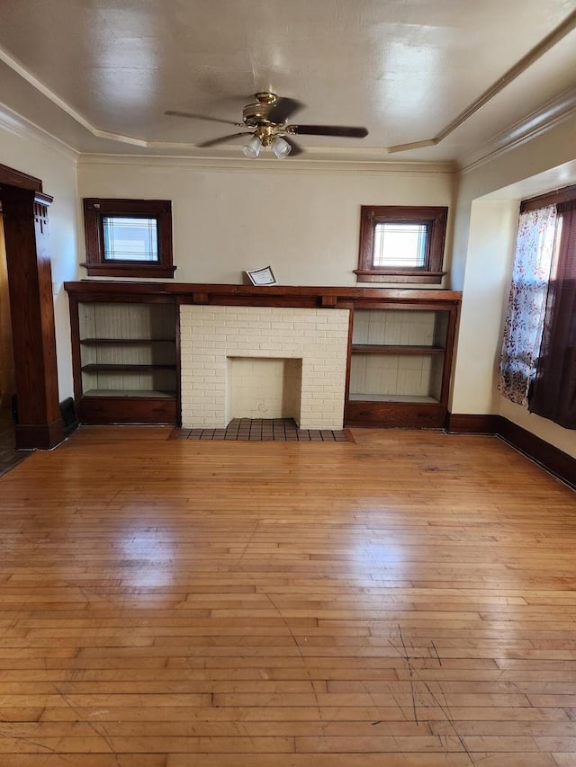 unfurnished living room featuring ceiling fan, plenty of natural light, light wood-type flooring, and a brick fireplace