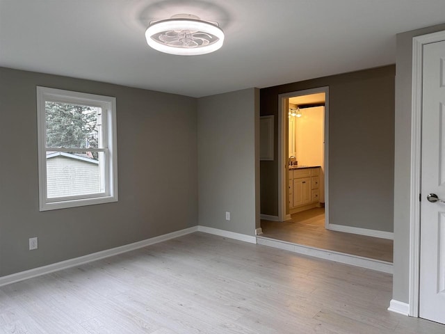 unfurnished bedroom with light hardwood / wood-style floors and connected bathroom