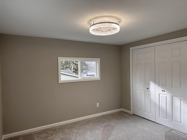 unfurnished bedroom with a closet and light colored carpet