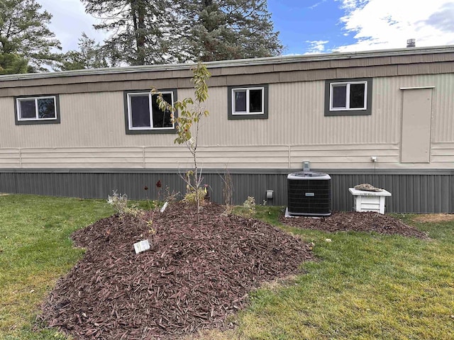 view of side of home featuring central air condition unit and a yard