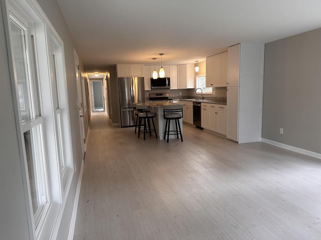 kitchen with stainless steel appliances, a kitchen bar, white cabinets, and a center island