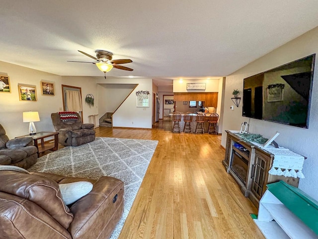 living room with a textured ceiling, hardwood / wood-style floors, and ceiling fan