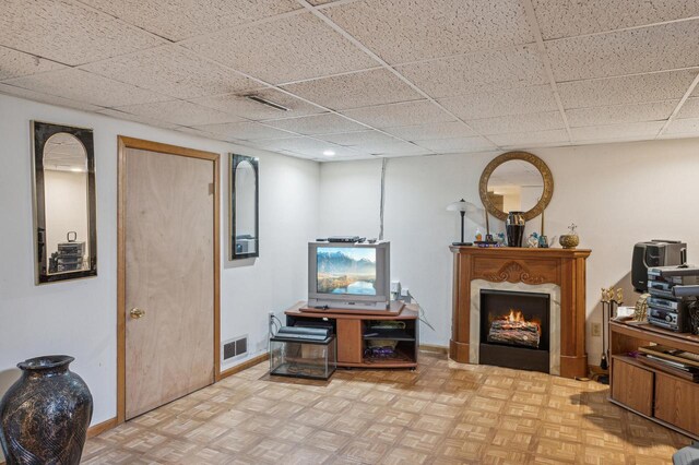 living area with light parquet flooring and a drop ceiling