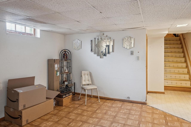 basement featuring a drop ceiling and light parquet floors