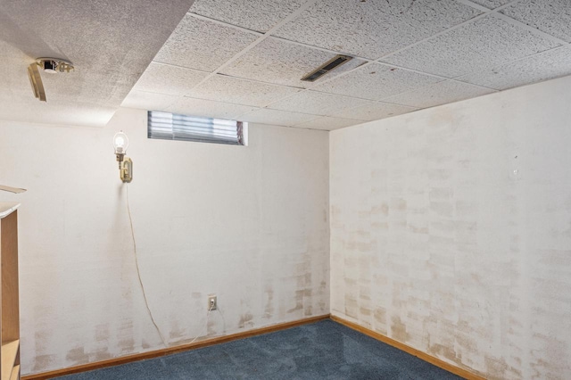 basement featuring a paneled ceiling and carpet