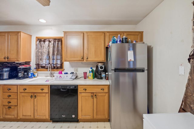 kitchen with decorative backsplash, black dishwasher, sink, and stainless steel refrigerator