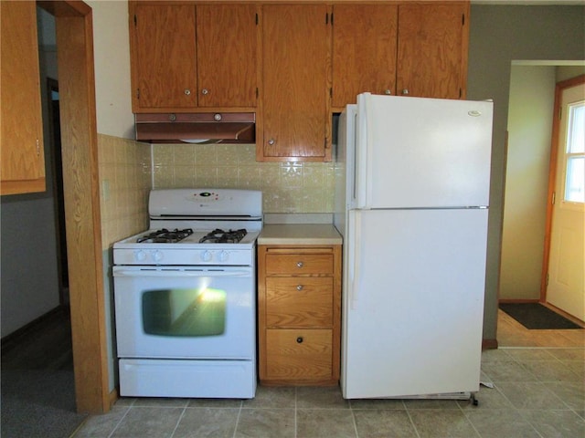 kitchen featuring decorative backsplash, light tile patterned floors, and white appliances