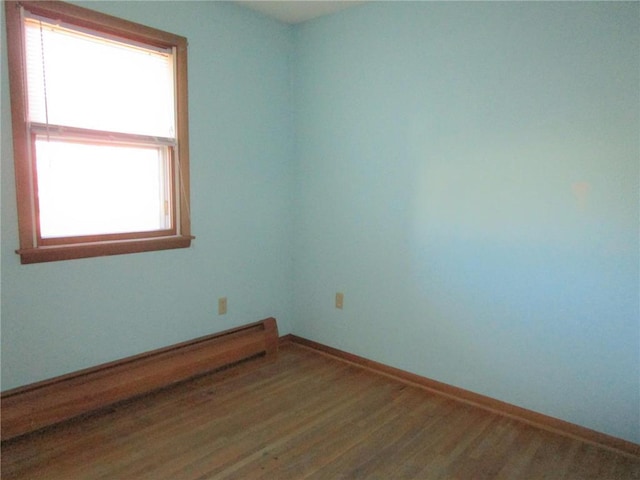 empty room with wood-type flooring and a baseboard radiator