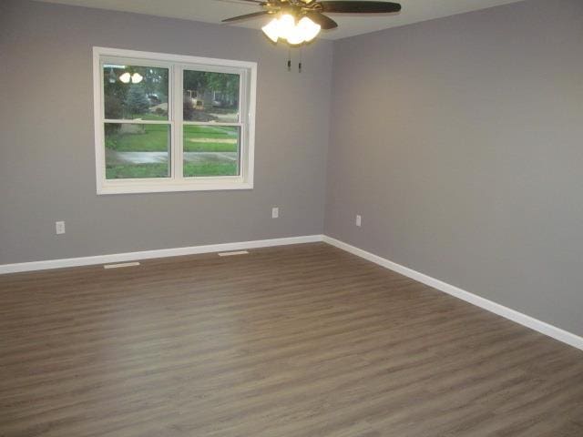 unfurnished room featuring dark wood-type flooring and ceiling fan