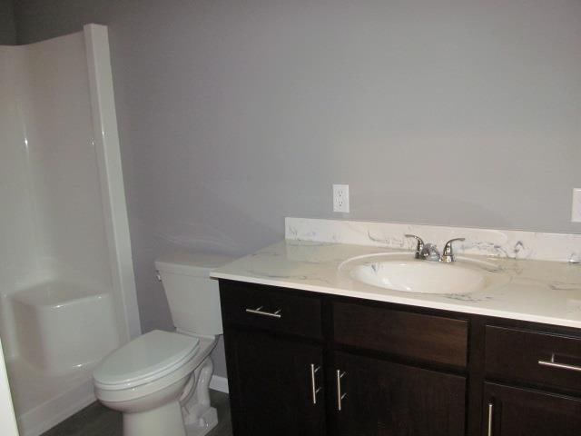 bathroom featuring walk in shower, vanity, and toilet