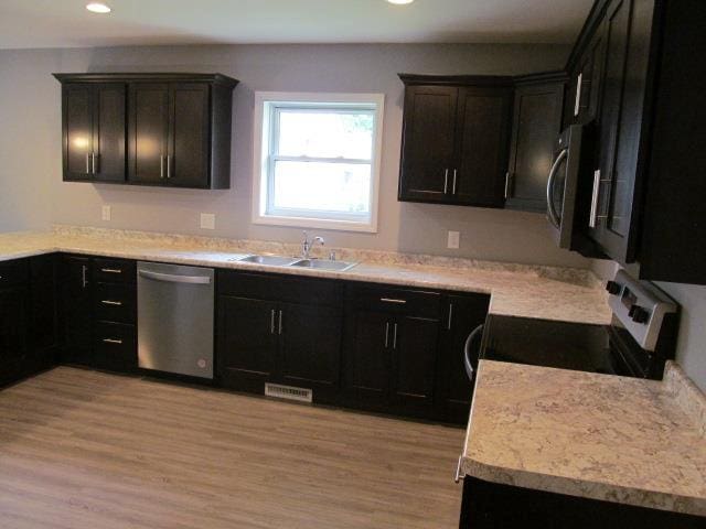 kitchen with stainless steel appliances, sink, and light hardwood / wood-style flooring