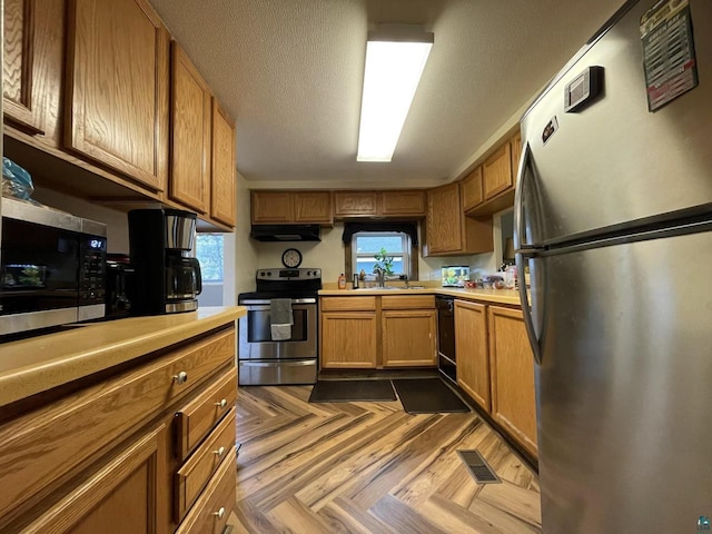 kitchen with a textured ceiling, sink, dark parquet flooring, and stainless steel appliances