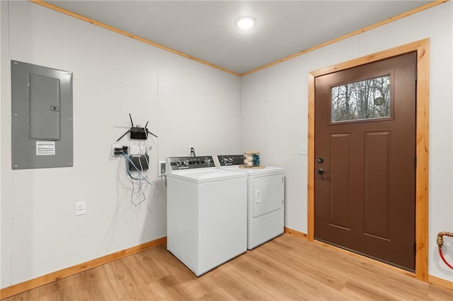 washroom with electric panel, light hardwood / wood-style flooring, washer and clothes dryer, and ornamental molding