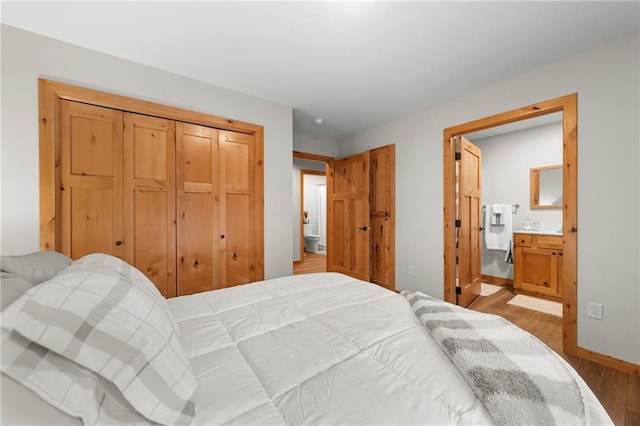 bedroom with light hardwood / wood-style floors, ensuite bath, and a closet