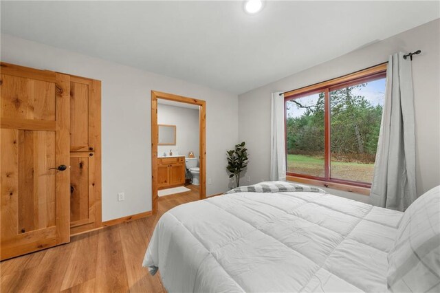 bedroom featuring connected bathroom and light hardwood / wood-style flooring