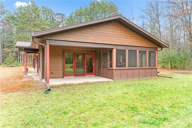 rear view of property with a lawn, a patio area, and a sunroom