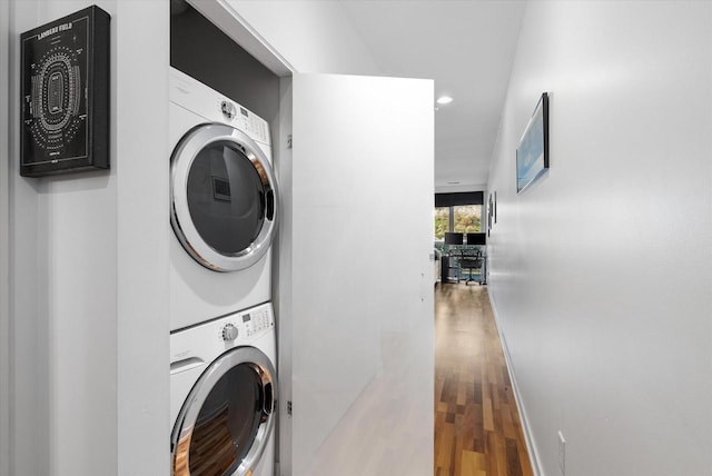 laundry room with hardwood / wood-style floors and stacked washer / dryer