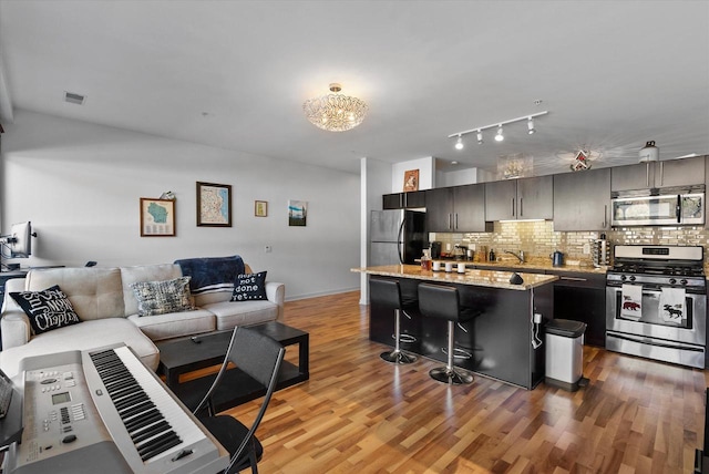 kitchen featuring light hardwood / wood-style floors, a kitchen bar, appliances with stainless steel finishes, and tasteful backsplash