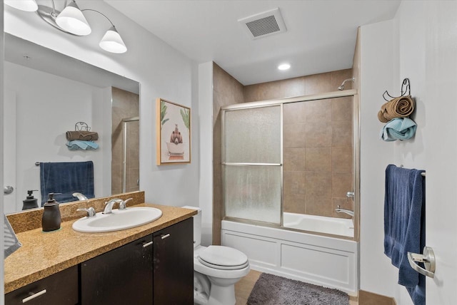 full bathroom with enclosed tub / shower combo, vanity, and toilet