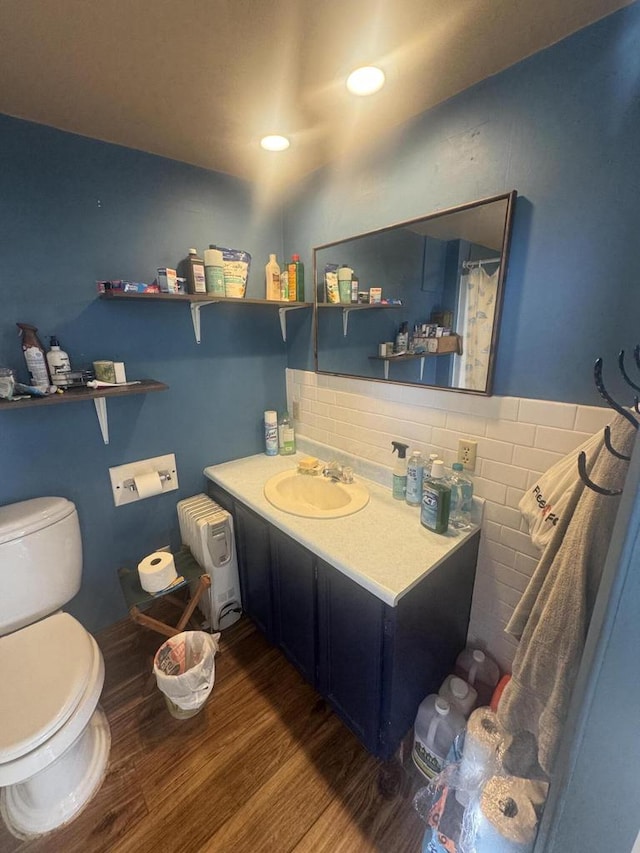 bathroom featuring toilet, wood-type flooring, tasteful backsplash, and vanity