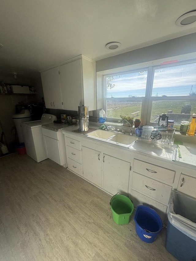 kitchen with sink, white cabinets, separate washer and dryer, and light hardwood / wood-style flooring