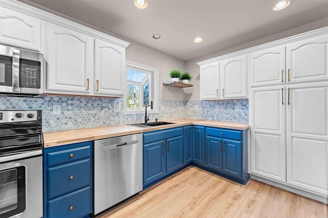 kitchen with white cabinetry, blue cabinetry, stainless steel appliances, and wooden counters