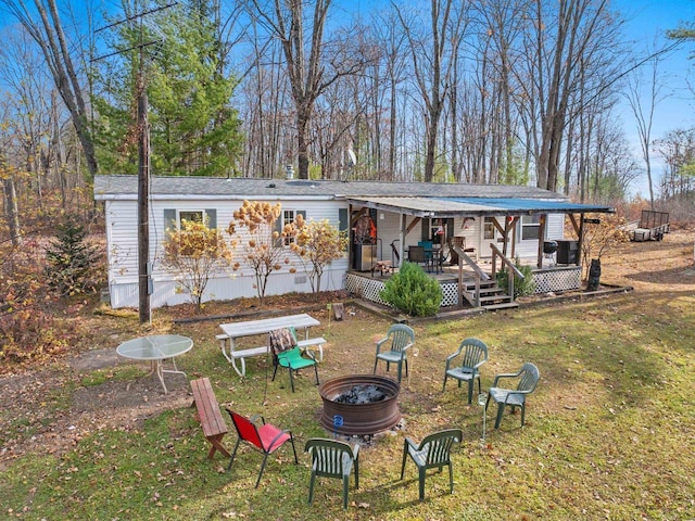 rear view of house with a deck, a lawn, and an outdoor fire pit