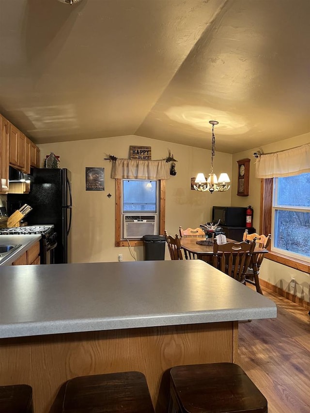 kitchen featuring kitchen peninsula, an inviting chandelier, decorative light fixtures, lofted ceiling, and light wood-type flooring