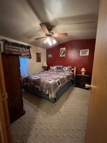 carpeted bedroom with ceiling fan and vaulted ceiling