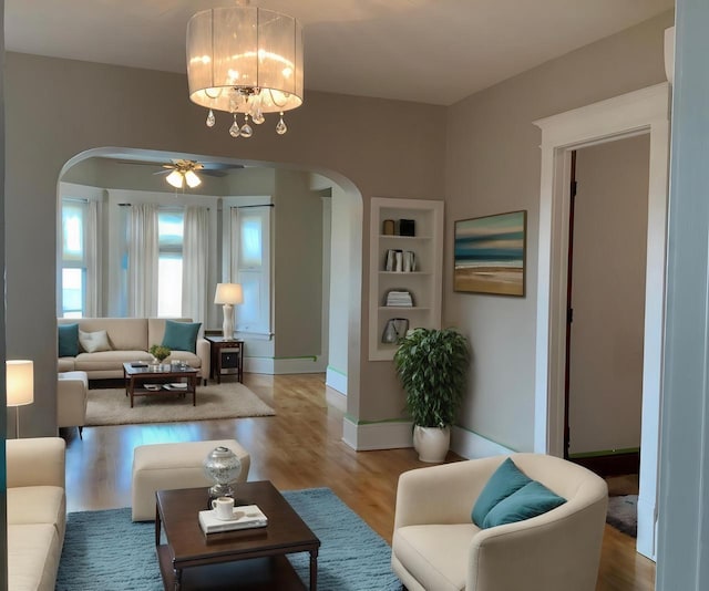 living room featuring ceiling fan with notable chandelier and hardwood / wood-style flooring