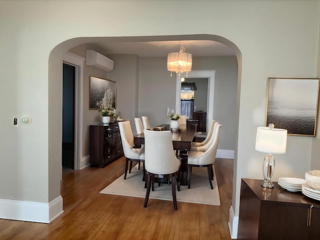 dining space with hardwood / wood-style flooring, a wall mounted AC, and a chandelier