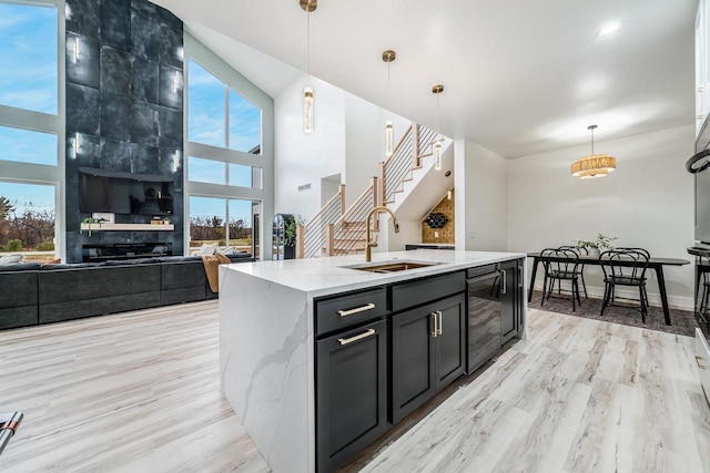 kitchen with sink, decorative light fixtures, an island with sink, and plenty of natural light