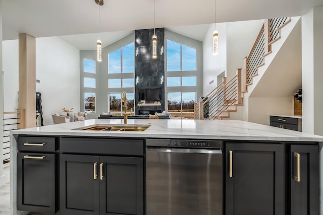 kitchen featuring dishwasher, pendant lighting, light stone counters, and a center island with sink