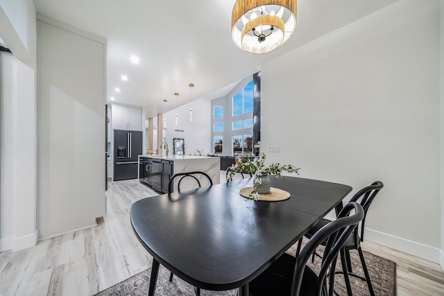 dining area featuring light wood-type flooring, a chandelier, and sink