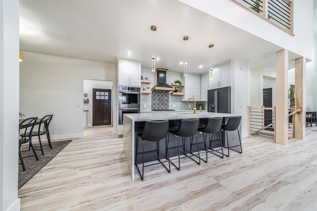 kitchen featuring white cabinetry, appliances with stainless steel finishes, tasteful backsplash, decorative light fixtures, and light wood-type flooring