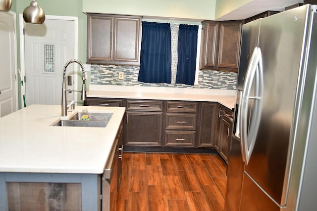 kitchen with stainless steel fridge, dark brown cabinetry, dark hardwood / wood-style flooring, decorative backsplash, and sink