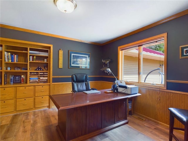 office area featuring wood walls, hardwood / wood-style floors, and crown molding