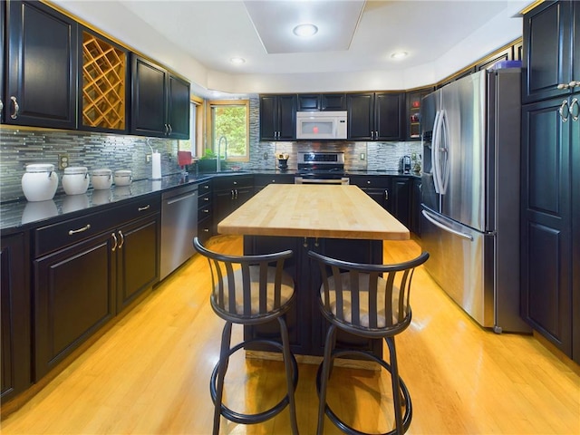 kitchen with backsplash, appliances with stainless steel finishes, sink, and light hardwood / wood-style floors