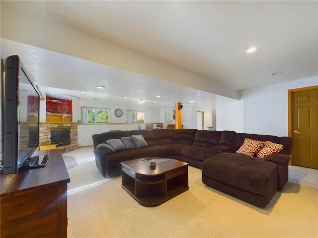 carpeted living room featuring a stone fireplace