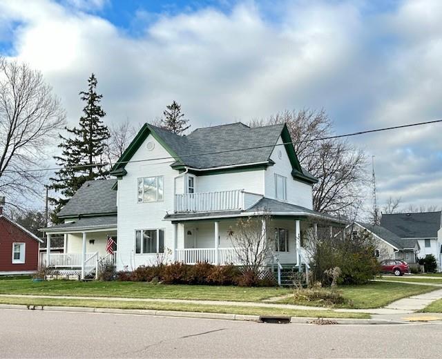 view of front of property featuring a porch, a front lawn, and a balcony