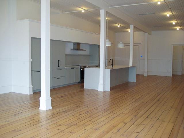 unfurnished living room featuring decorative columns, light wood-style flooring, and a sink