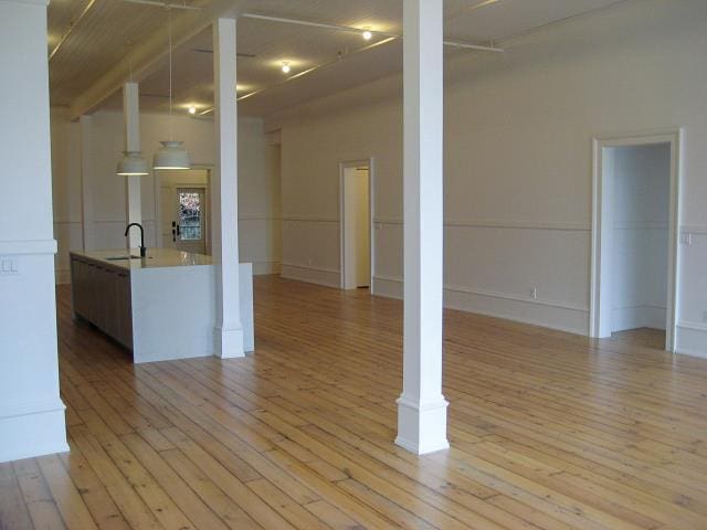 unfurnished living room with a sink and light wood-style floors