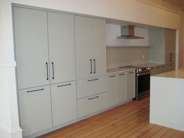 kitchen featuring white cabinets, light hardwood / wood-style flooring, wall chimney exhaust hood, and stainless steel range with electric stovetop