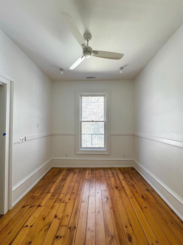 spare room with baseboards, light wood-type flooring, and ceiling fan