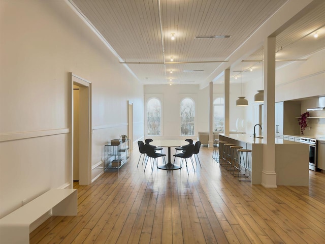 dining space with light hardwood / wood-style flooring, wooden ceiling, and sink