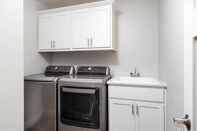 clothes washing area featuring washer and clothes dryer, cabinets, and sink