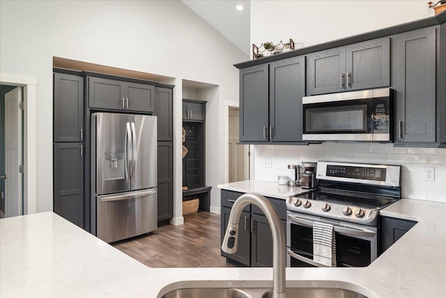 kitchen featuring high vaulted ceiling, stainless steel appliances, dark hardwood / wood-style floors, and backsplash