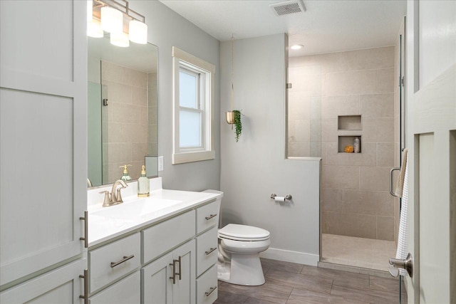 bathroom featuring toilet, vanity, and a tile shower