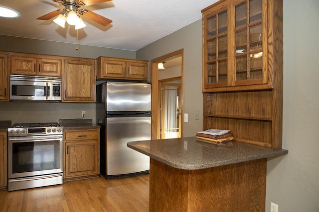 kitchen featuring ceiling fan, light hardwood / wood-style floors, kitchen peninsula, and stainless steel appliances