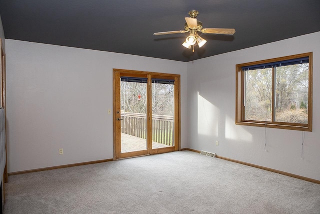 empty room featuring a wealth of natural light, ceiling fan, and light carpet